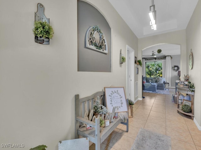 hallway featuring tile patterned flooring, arched walkways, and baseboards