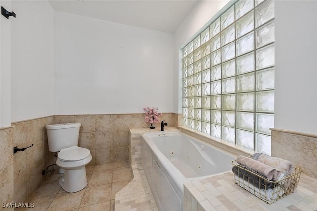 1240 Desoto Blvd S, Naples, FL 34117 - bathroom featuring a tub with jets, wainscoting, tile walls, and tile patterned floors
