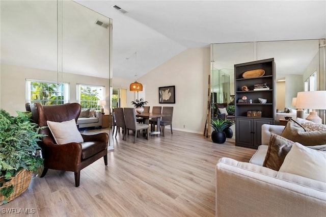 living area featuring light wood-style flooring, visible vents, vaulted ceiling, and baseboards