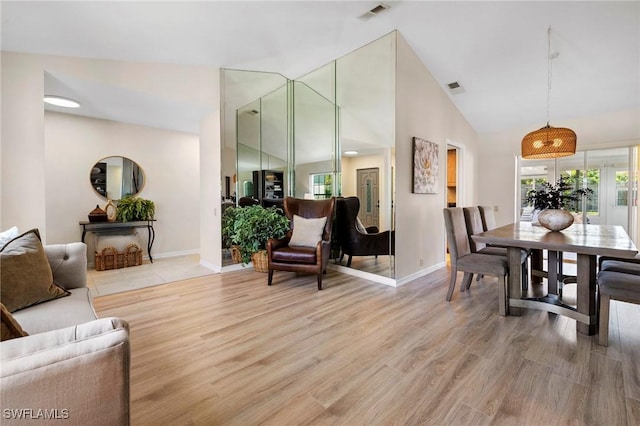 living area featuring light wood-style floors, visible vents, high vaulted ceiling, and baseboards