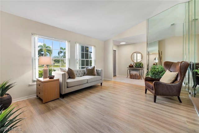 sitting room featuring lofted ceiling, light wood-style flooring, and baseboards