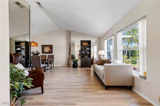 living area with visible vents, vaulted ceiling, light wood-style flooring, and baseboards