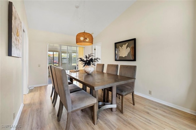 dining room featuring light wood-style floors, vaulted ceiling, and baseboards