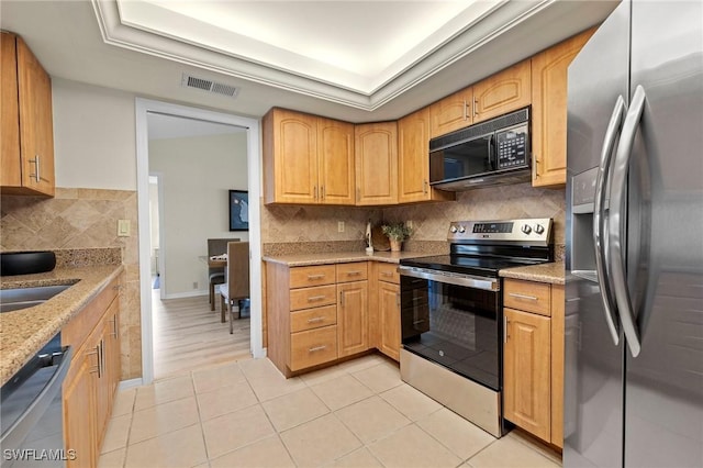 kitchen featuring stainless steel appliances, a raised ceiling, visible vents, and light stone countertops