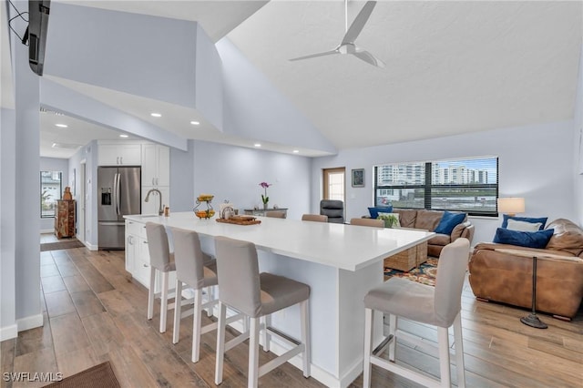 8080 Lagoon Rd, Fort Myers Beach, FL 33931 - kitchen with stainless steel fridge with ice dispenser, a breakfast bar, white cabinets, open floor plan, and recessed lighting