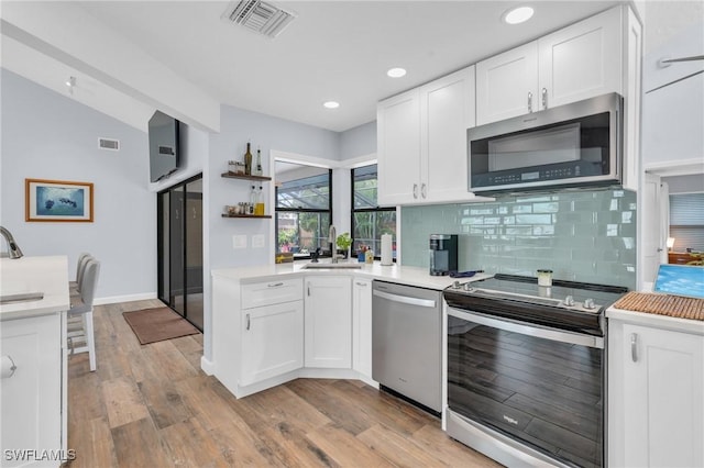 8080 Lagoon Rd, Fort Myers Beach, FL 33931 - kitchen with appliances with stainless steel finishes, vaulted ceiling, decorative backsplash, white cabinets, and light countertops