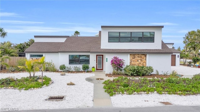 8080 Lagoon Rd, Fort Myers Beach, FL 33931 - contemporary home with stucco siding, a shingled roof, fence, and stone siding