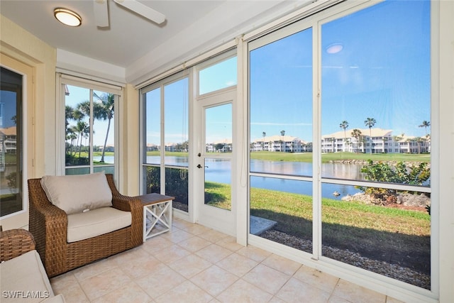 sunroom / solarium featuring a water view, a residential view, and a ceiling fan