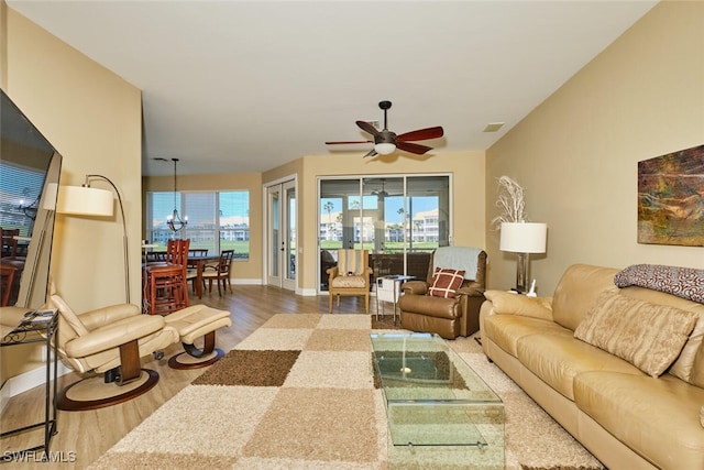 living room featuring a ceiling fan, baseboards, visible vents, and wood finished floors