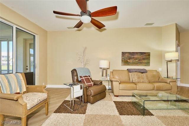 living area with light wood-type flooring, baseboards, and a ceiling fan