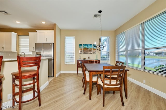 dining area with a chandelier, visible vents, and light wood finished floors