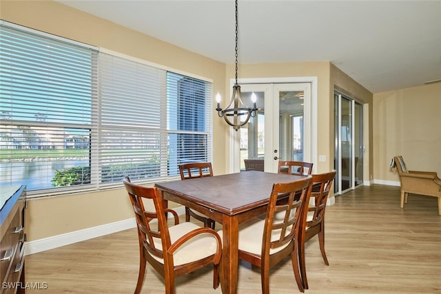 dining space featuring light wood-style floors, baseboards, and an inviting chandelier