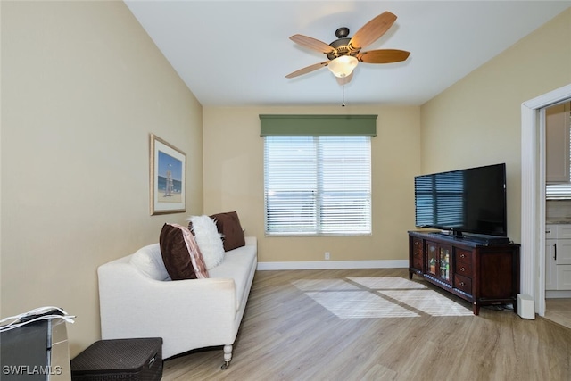 living area with baseboards, ceiling fan, and light wood finished floors