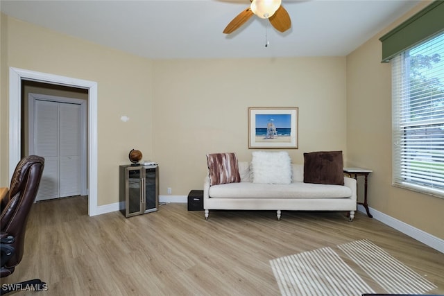 living area with light wood-style floors, ceiling fan, and baseboards