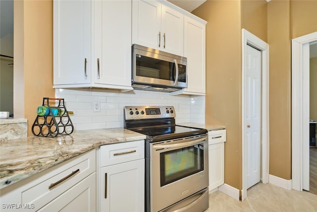 kitchen featuring stainless steel appliances, decorative backsplash, light tile patterned flooring, white cabinetry, and light stone countertops