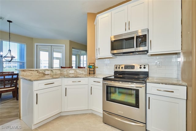 kitchen featuring tasteful backsplash, appliances with stainless steel finishes, decorative light fixtures, a peninsula, and white cabinetry