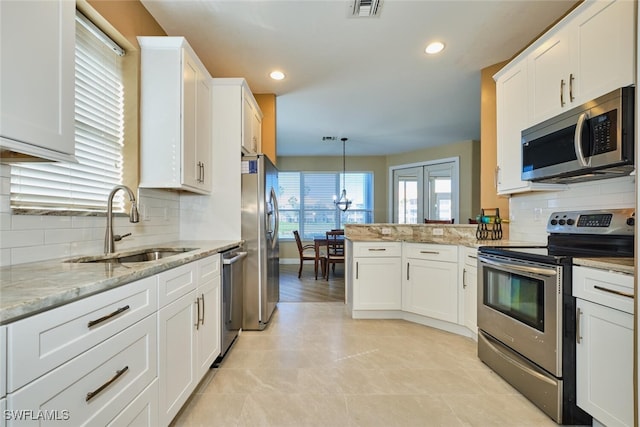 kitchen with a sink, visible vents, white cabinets, appliances with stainless steel finishes, and decorative light fixtures