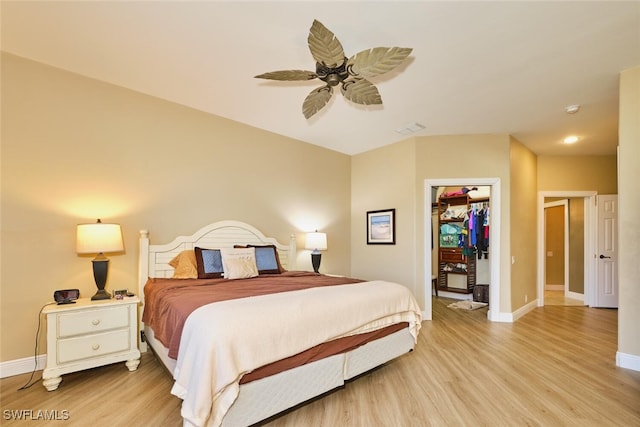 bedroom with visible vents, light wood-style flooring, baseboards, and a spacious closet