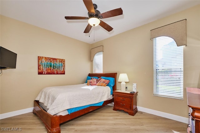 bedroom with a ceiling fan, light wood-type flooring, multiple windows, and baseboards