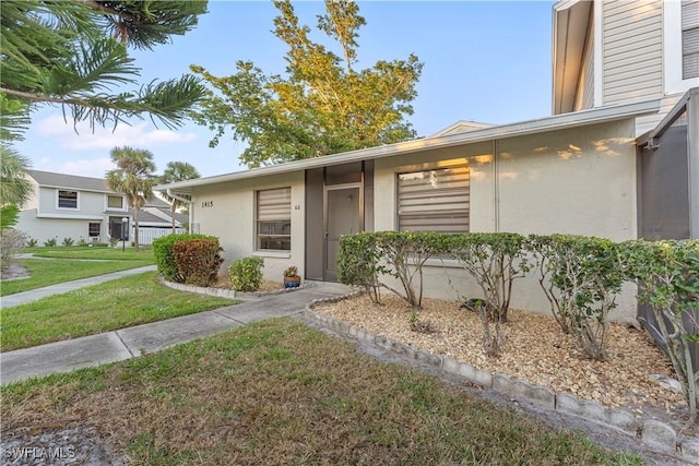 entrance to property featuring a yard and stucco siding