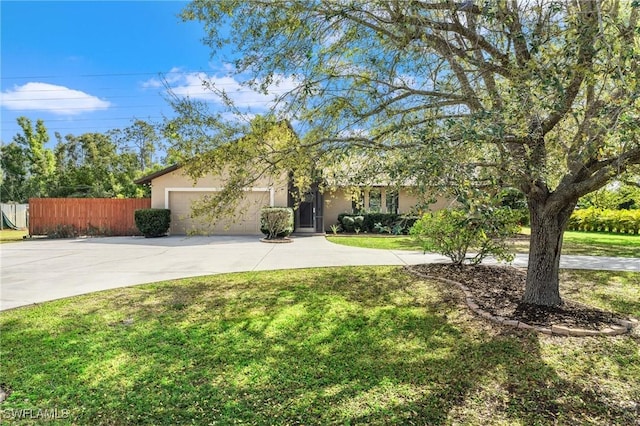 view of front of property with stucco siding, concrete driveway, fence, a garage, and a front lawn