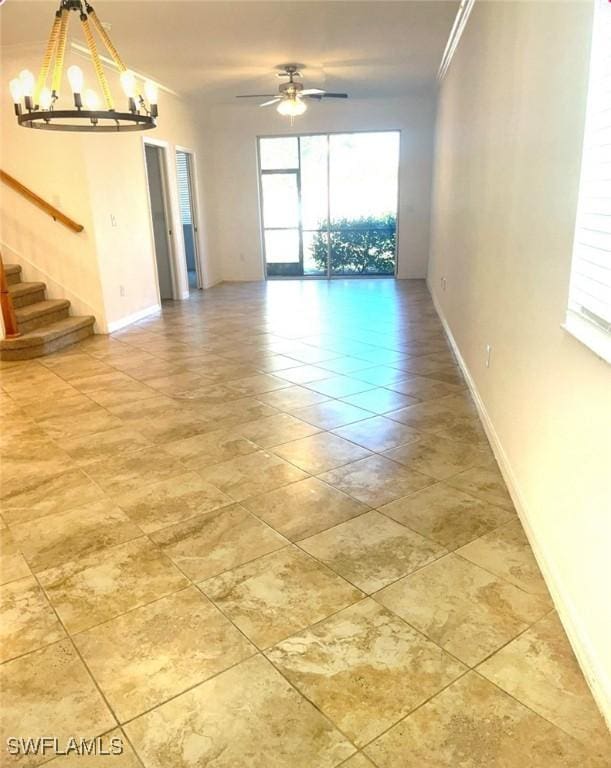 unfurnished room with baseboards, stairway, crown molding, and ceiling fan with notable chandelier