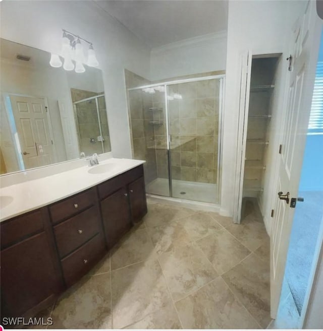 bathroom featuring double vanity, ornamental molding, a stall shower, a sink, and tile patterned flooring