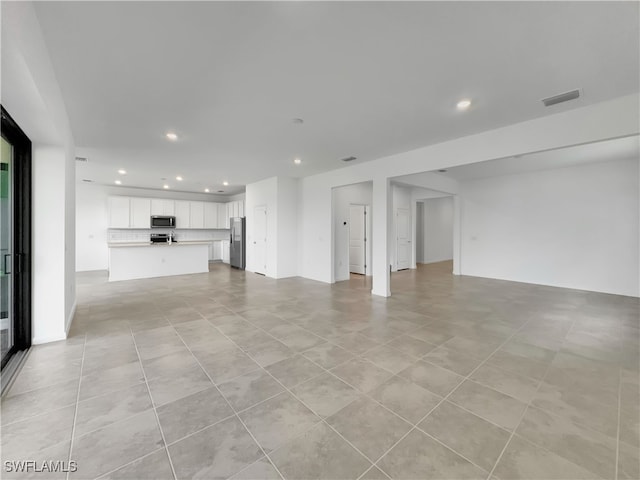 unfurnished living room with recessed lighting and visible vents