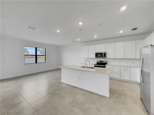 kitchen with a kitchen island with sink, appliances with stainless steel finishes, light countertops, and a sink