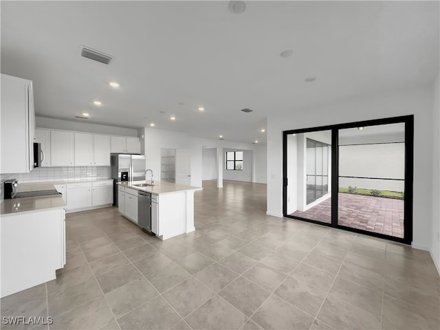 kitchen with stainless steel appliances, light countertops, visible vents, a kitchen island with sink, and white cabinetry