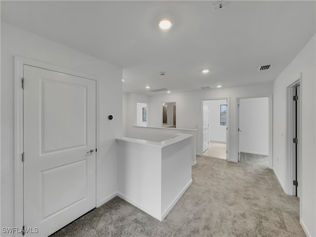 kitchen featuring baseboards, visible vents, light colored carpet, a peninsula, and light countertops