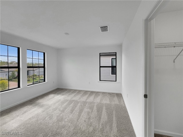 unfurnished bedroom featuring baseboards, visible vents, and light colored carpet