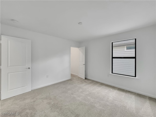 empty room featuring light carpet and baseboards