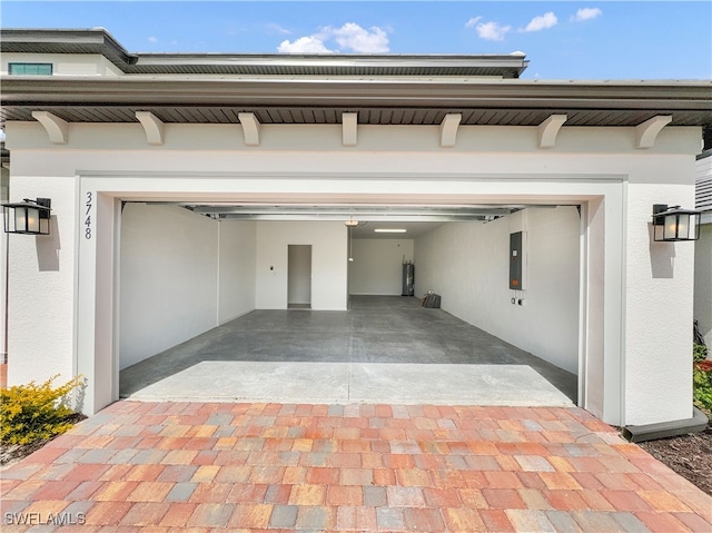 garage with decorative driveway and electric panel