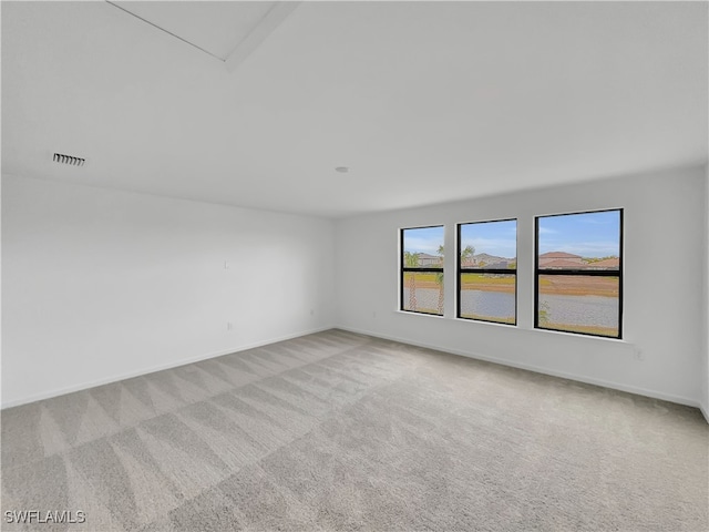 unfurnished room featuring light carpet, visible vents, and baseboards