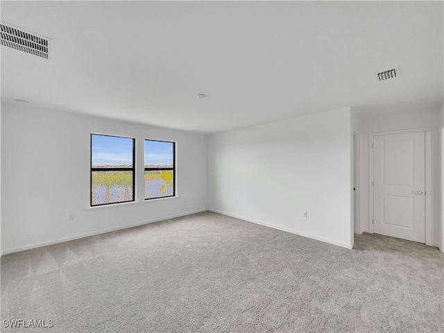 unfurnished room featuring light colored carpet, visible vents, and baseboards