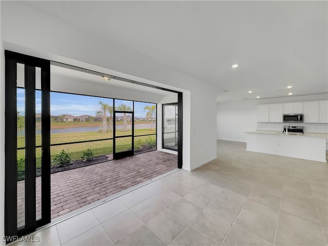 unfurnished living room featuring recessed lighting, a sink, and light tile patterned floors