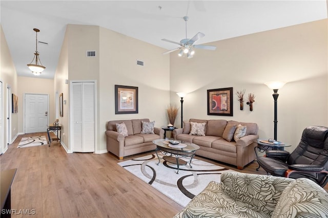 living room featuring high vaulted ceiling, visible vents, and light wood finished floors