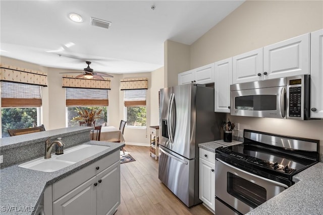 kitchen featuring visible vents, appliances with stainless steel finishes, light wood-style floors, white cabinetry, and a sink