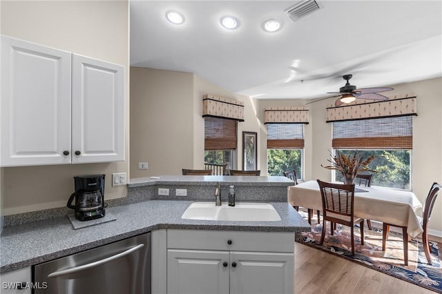 kitchen with a peninsula, a sink, visible vents, white cabinetry, and dishwasher