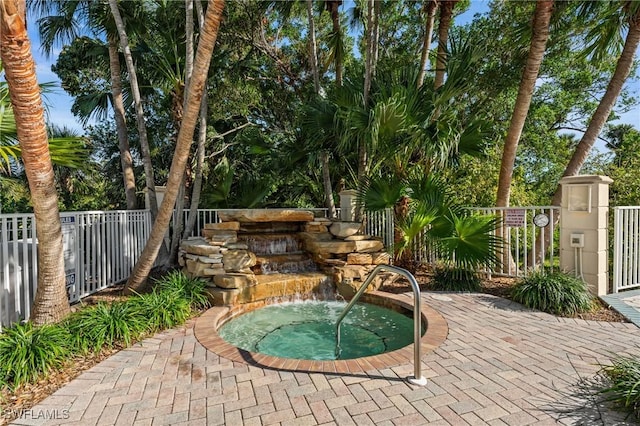 view of swimming pool with a community hot tub and fence