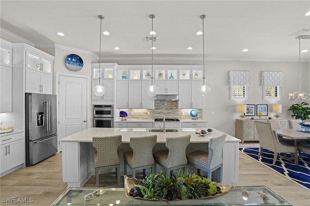 kitchen featuring a center island with sink, visible vents, light wood-style flooring, appliances with stainless steel finishes, and ornamental molding