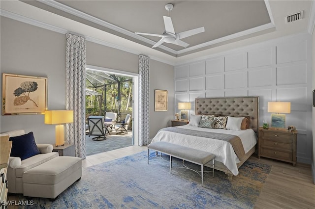 bedroom featuring a tray ceiling, access to outside, and crown molding