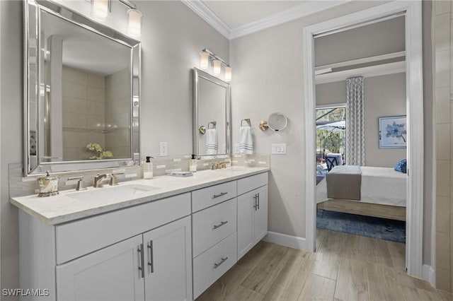 bathroom with connected bathroom, wood finished floors, a sink, decorative backsplash, and crown molding