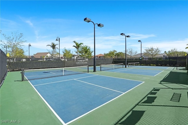 view of tennis court with community basketball court and fence