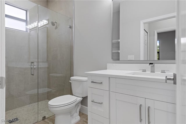 bathroom with a stall shower, baseboards, vanity, and toilet