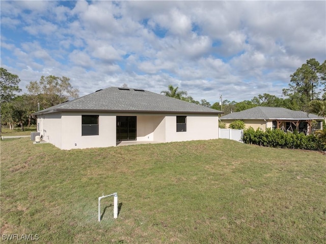 rear view of property with a yard, fence, and stucco siding