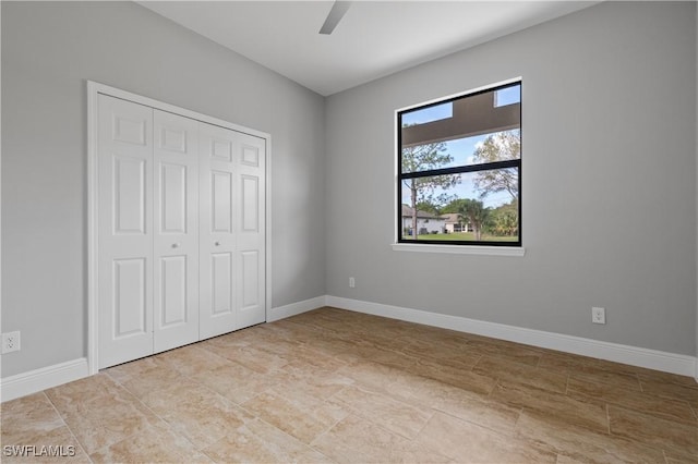 unfurnished bedroom with a closet, ceiling fan, and baseboards