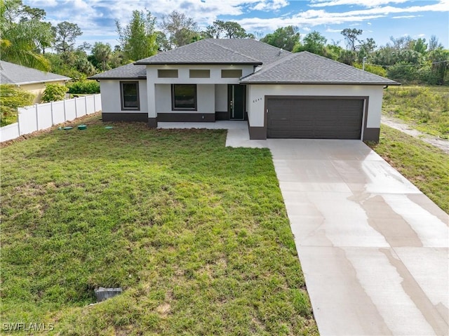 prairie-style home with a garage, fence, driveway, stucco siding, and a front lawn