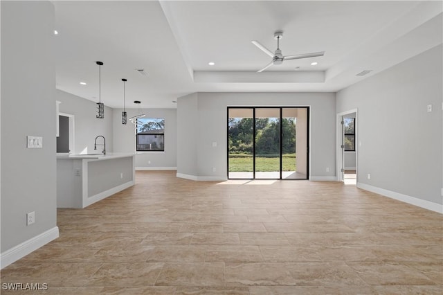 unfurnished living room with a sink, baseboards, and a ceiling fan